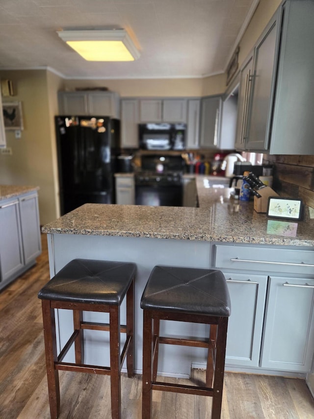 134 Minuteman Dr, Millinocket, ME 04462 - kitchen with black appliances, gray cabinets, a kitchen breakfast bar, and light stone counters