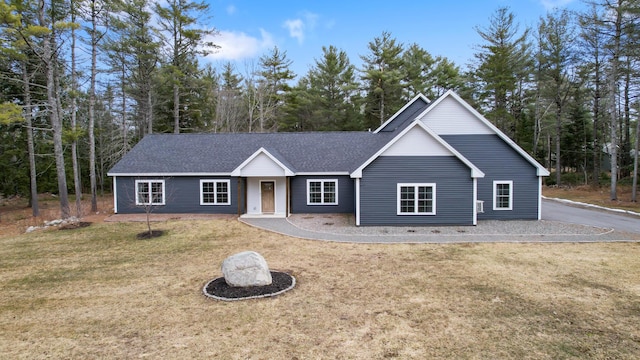 view of front of house featuring roof with shingles and a front yard