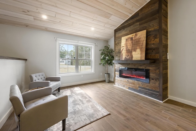 living area featuring a stone fireplace, wood ceiling, wood finished floors, lofted ceiling, and baseboards