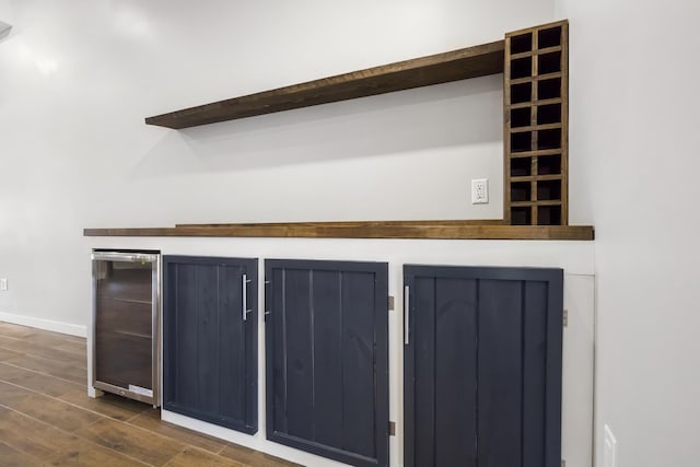 room details with wine cooler, wood finished floors, baseboards, and a dry bar