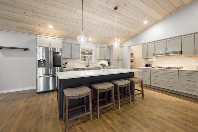 kitchen featuring vaulted ceiling, a center island, appliances with stainless steel finishes, wood ceiling, and under cabinet range hood