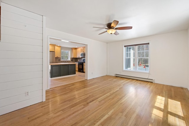 573 Exeter Rd, Corinth, ME 04427 - unfurnished living room featuring a baseboard heating unit, a ceiling fan, light wood-style flooring, baseboards, and a sink