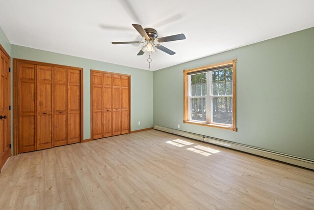 573 Exeter Rd, Corinth, ME 04427 - unfurnished bedroom featuring multiple closets, baseboard heating, light wood finished floors, and a ceiling fan