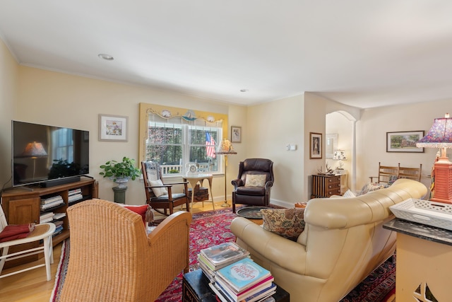 living room with arched walkways, ornamental molding, and wood finished floors