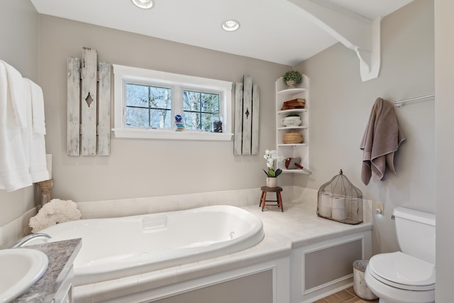 bathroom with toilet, a garden tub, and vanity