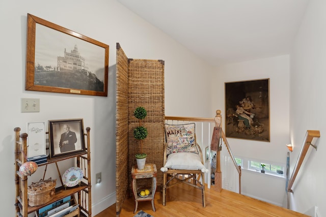 sitting room featuring baseboards, an upstairs landing, and wood finished floors