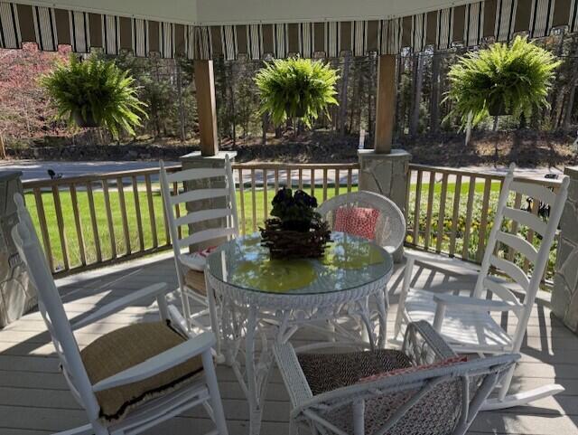 deck with outdoor dining area and a yard