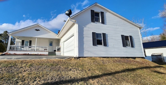 view of front facade featuring driveway, covered porch, and an attached garage