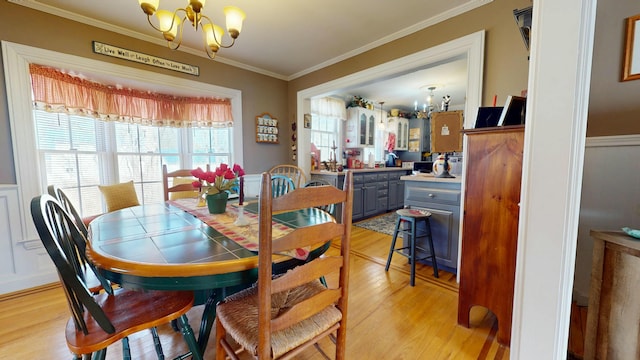 150 Enfield Rd, Lincoln, ME 04457 - dining space featuring a notable chandelier, a decorative wall, ornamental molding, light wood-type flooring, and wainscoting