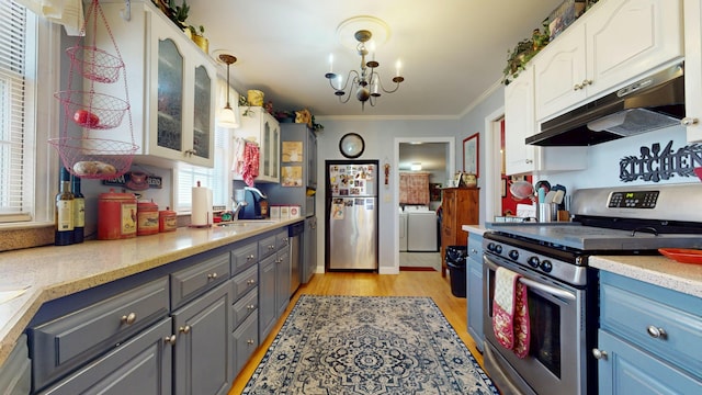 150 Enfield Rd, Lincoln, ME 04457 - kitchen with glass insert cabinets, ornamental molding, under cabinet range hood, washer / dryer, and stainless steel appliances
