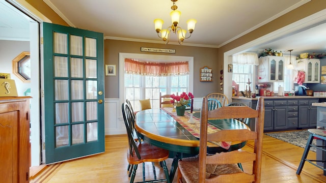 150 Enfield Rd, Lincoln, ME 04457 - dining area with a chandelier, crown molding, a wainscoted wall, and light wood-type flooring