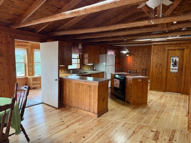 160 Pinkhams Cove Rd, Belgrade, ME 04917 - kitchen featuring wooden walls, beamed ceiling, light wood-type flooring, and black range with electric stovetop
