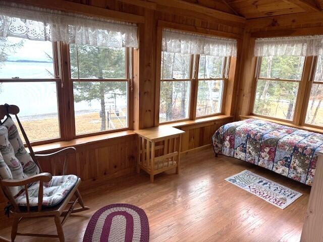 160 Pinkhams Cove Rd, Belgrade, ME 04917 - bedroom with wooden walls, vaulted ceiling, and light wood-type flooring