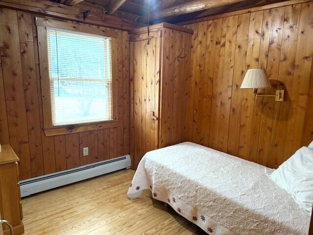 160 Pinkhams Cove Rd, Belgrade, ME 04917 - bedroom featuring wood finished floors, a baseboard heating unit, wooden walls, and beam ceiling