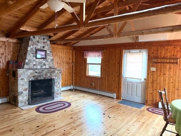 160 Pinkhams Cove Rd, Belgrade, ME 04917 - unfurnished living room with wooden walls, ceiling fan, lofted ceiling with beams, a baseboard heating unit, and hardwood / wood-style flooring