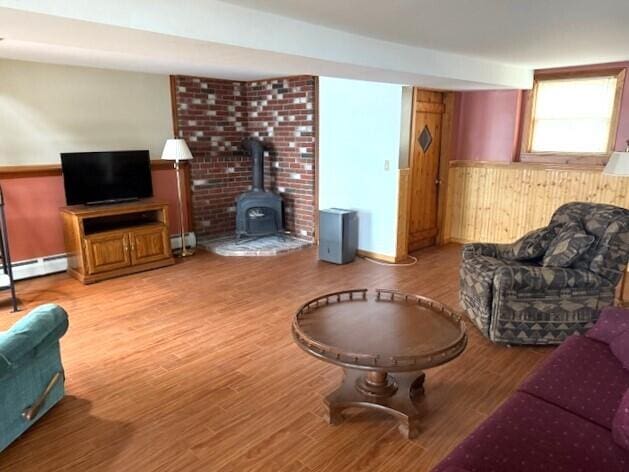 160 Pinkhams Cove Rd, Belgrade, ME 04917 - living area with a baseboard radiator, a wood stove, a baseboard heating unit, and wood finished floors