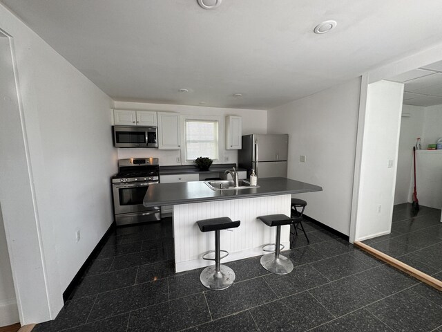 159 Elm St, Bangor, ME 04401 - kitchen featuring stainless steel appliances, a sink, white cabinets, baseboards, and dark countertops