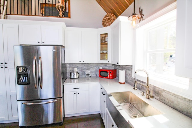 28 First St, Bethel, ME 04217 - kitchen with freestanding refrigerator, a sink, decorative backsplash, white cabinetry, and lofted ceiling