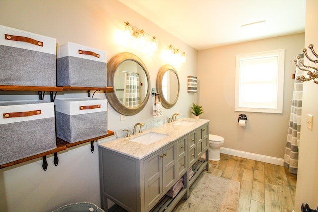28 First St, Bethel, ME 04217 - bathroom with wood finished floors, baseboards, double vanity, and toilet