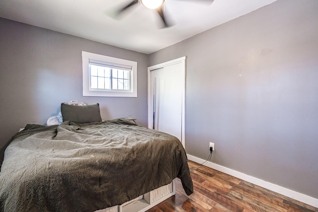 bedroom featuring dark wood-style flooring, baseboards, a ceiling fan, and a closet