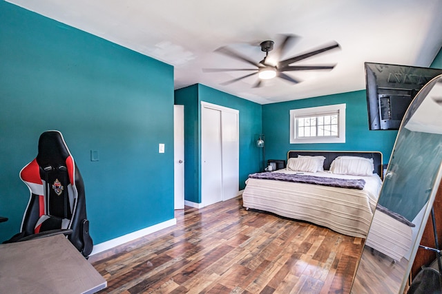 bedroom featuring a closet, a ceiling fan, baseboards, and wood finished floors