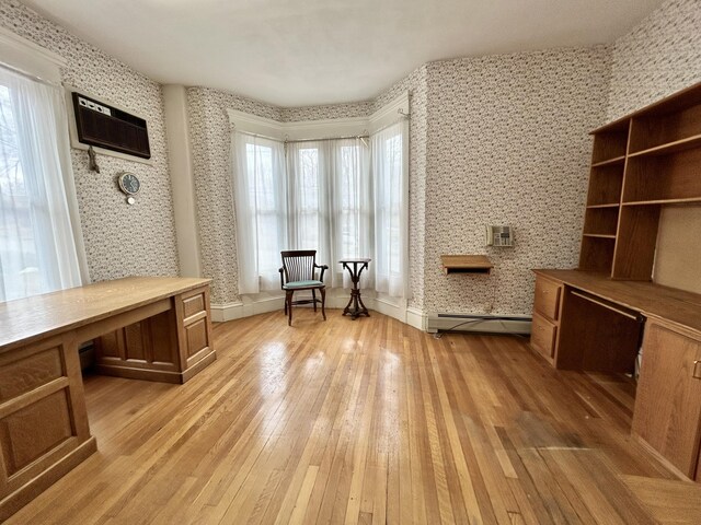 living area featuring baseboards, baseboard heating, wallpapered walls, and light wood-style flooring