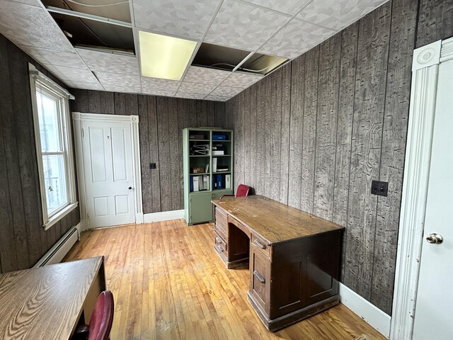 home office featuring wood walls, baseboards, an ornate ceiling, a baseboard heating unit, and light wood-style flooring