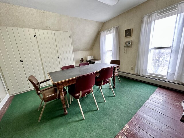 dining room featuring a baseboard radiator, wood-type flooring, and lofted ceiling