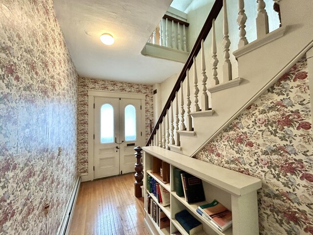 foyer entrance featuring stairway, a baseboard radiator, light wood-type flooring, and wallpapered walls