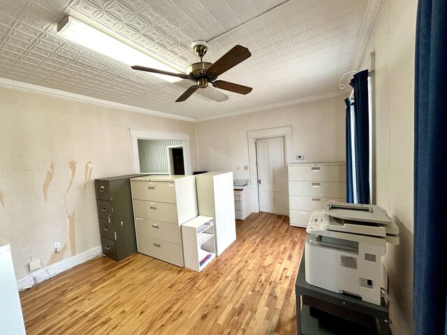 interior space with crown molding, light wood finished floors, an ornate ceiling, a ceiling fan, and baseboards