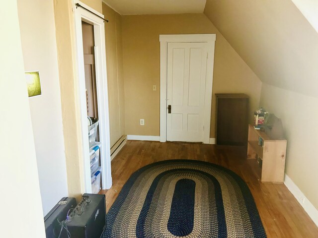 interior space featuring baseboard heating, baseboards, vaulted ceiling, and wood finished floors