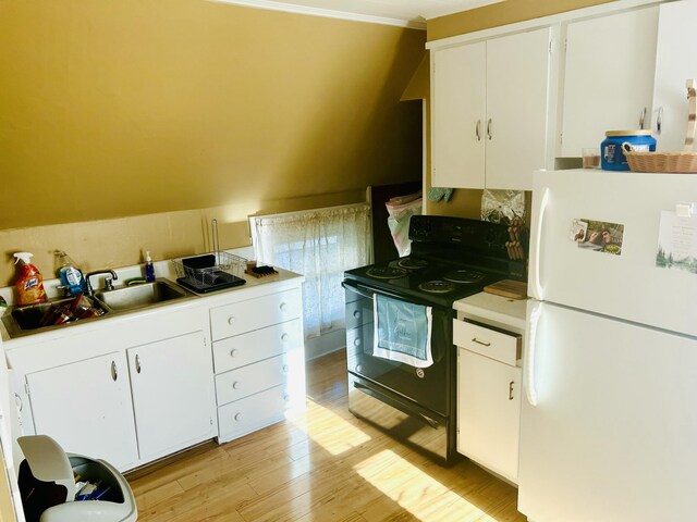 kitchen featuring black electric range, light countertops, a sink, freestanding refrigerator, and light wood-style floors