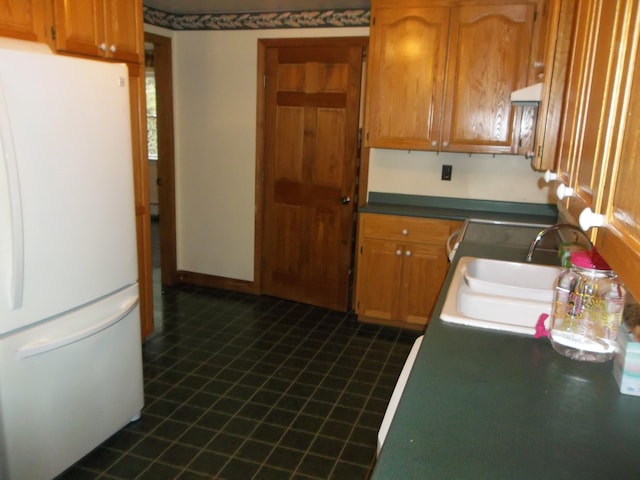 8 Varney Loop, Crawford, ME 04694 - kitchen featuring freestanding refrigerator, under cabinet range hood, brown cabinetry, and a sink