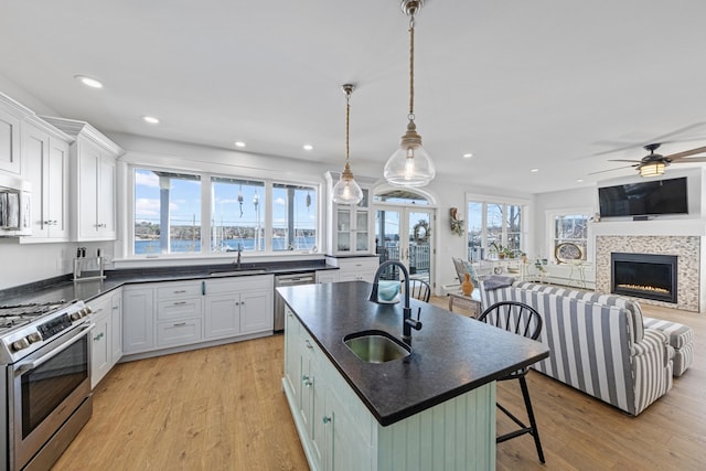 51 Bridge St, Belfast, ME 04915 - kitchen featuring a kitchen breakfast bar, a tiled fireplace, light wood-style flooring, white cabinetry, and appliances with stainless steel finishes
