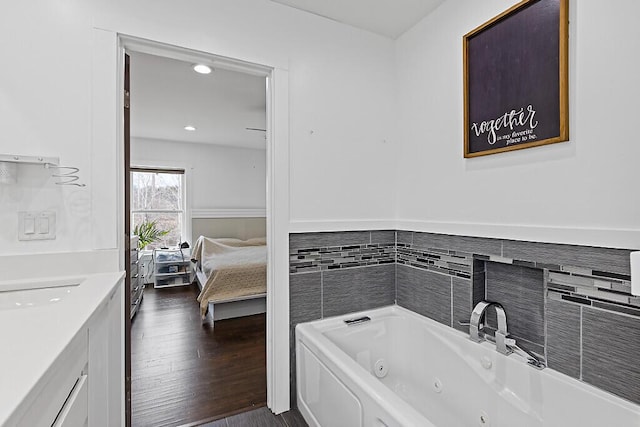 ensuite bathroom with recessed lighting, wood finished floors, a jetted tub, vanity, and connected bathroom