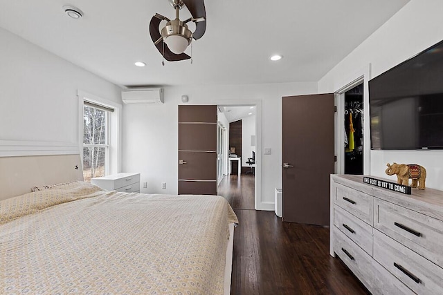 bedroom with recessed lighting, a wall mounted air conditioner, a spacious closet, dark wood-type flooring, and ceiling fan