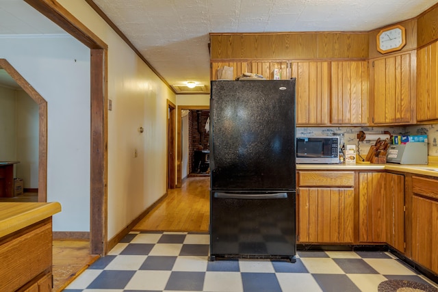 927 Pleasant St, Blue Hill, ME 04614 - kitchen with freestanding refrigerator, stainless steel microwave, light floors, light countertops, and crown molding