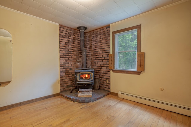927 Pleasant St, Blue Hill, ME 04614 - unfurnished living room featuring a baseboard radiator, a wood stove, crown molding, hardwood / wood-style flooring, and baseboards