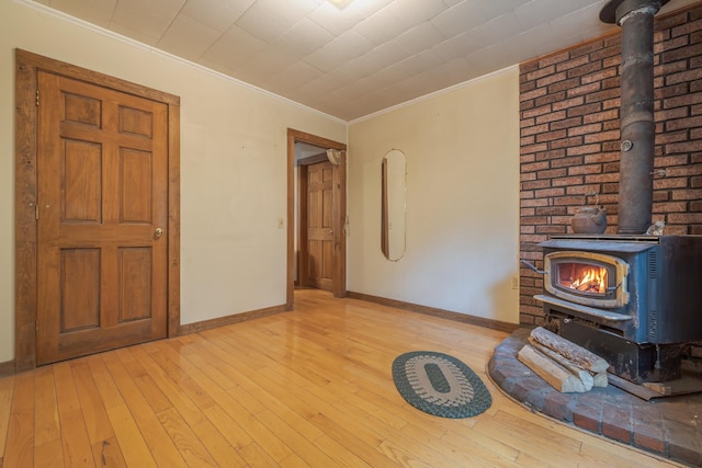 927 Pleasant St, Blue Hill, ME 04614 - unfurnished living room featuring a wood stove, crown molding, light wood-type flooring, and baseboards