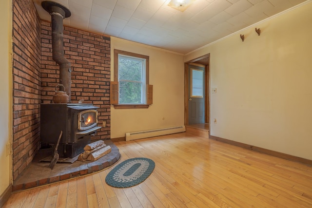 927 Pleasant St, Blue Hill, ME 04614 - unfurnished living room featuring baseboard heating, a wood stove, baseboards, hardwood / wood-style floors, and crown molding