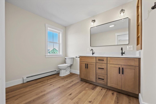 bathroom with hardwood / wood-style flooring, toilet, a baseboard heating unit, and a sink