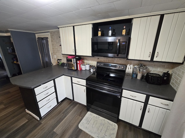 kitchen with stainless steel microwave, dark countertops, dark wood-style floors, and black / electric stove