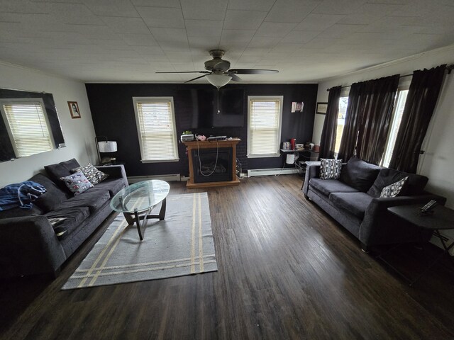 living area with a baseboard radiator, baseboards, a fireplace with raised hearth, wood finished floors, and ceiling fan