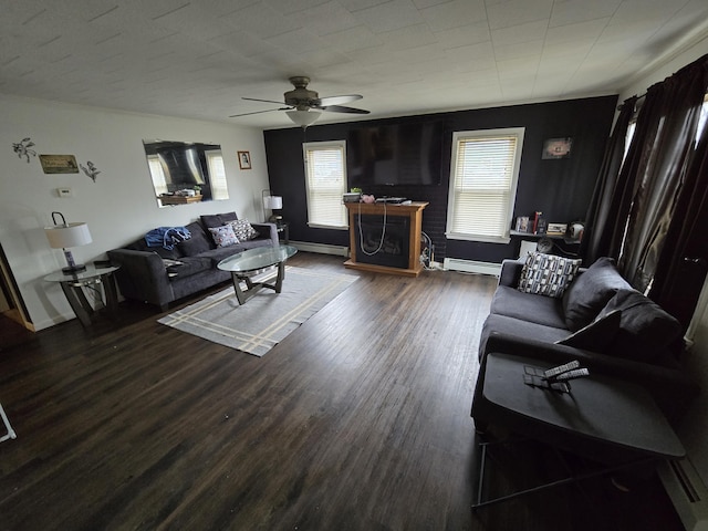 living area with dark wood-style floors, ceiling fan, a baseboard heating unit, and a healthy amount of sunlight