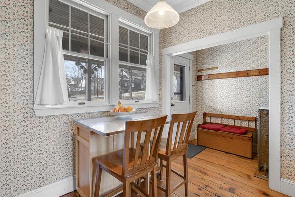 interior space featuring baseboards, wallpapered walls, and wood finished floors