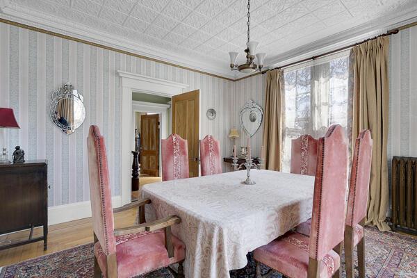 dining space with ornamental molding, wood finished floors, radiator heating unit, wallpapered walls, and a notable chandelier