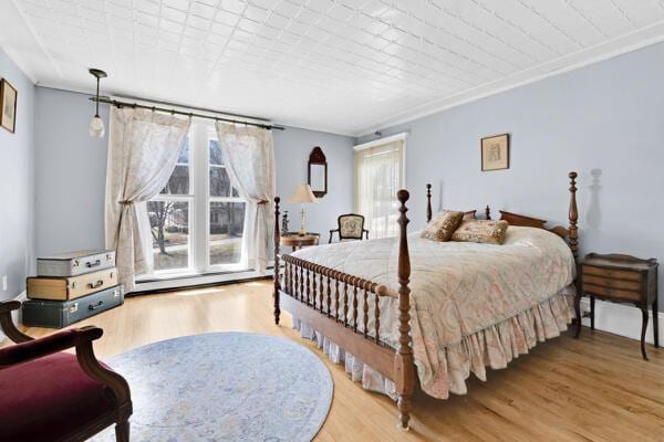 bedroom with a baseboard heating unit and wood finished floors