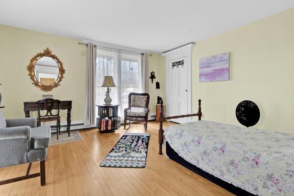 bedroom with baseboard heating and wood finished floors