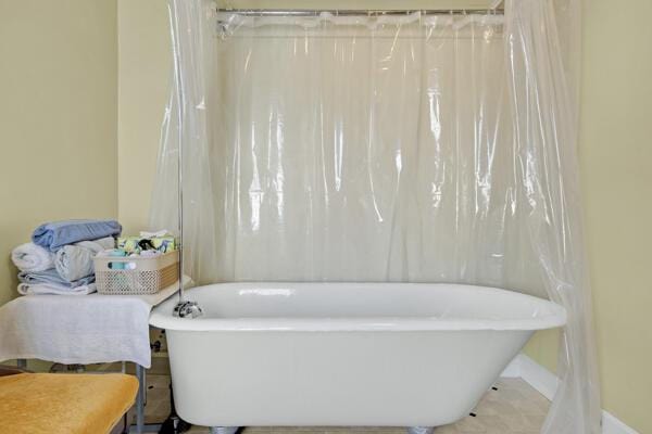 full bath with baseboards, a soaking tub, and tile patterned floors