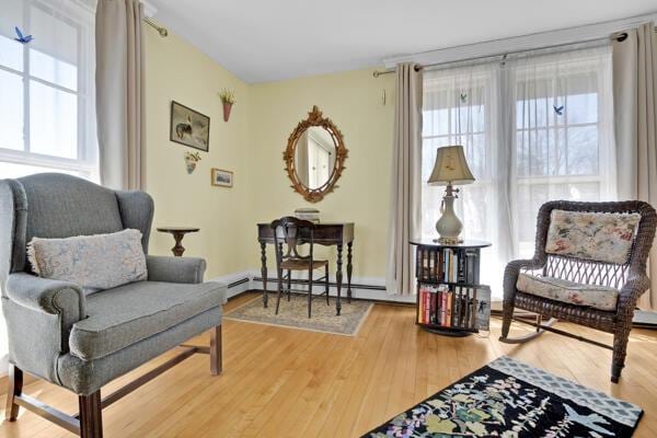 living area featuring a baseboard heating unit and wood finished floors